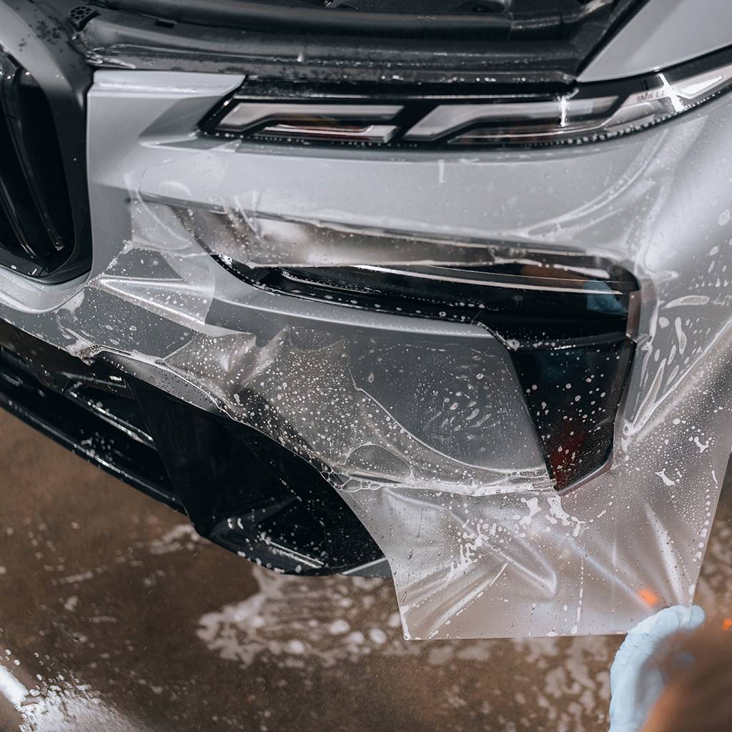 Neuwagen bei der Verklebung einer transparenten Lackschutzfolie auf der Motorhaube